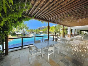 An outdoor pool area with a pergola, seating, and a view of the pool. - Wai Wai Cumbuco Resort (Caucaia)