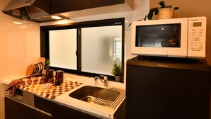 Angolo cottura funzionale con forno a microonde, lavandino e tagliere a scacchi.