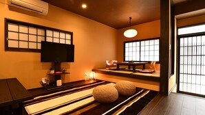 Una camera tradizionale in stile giapponese, con pavimento in tatami, un tavolino, una televisione e una porta scorrevole.