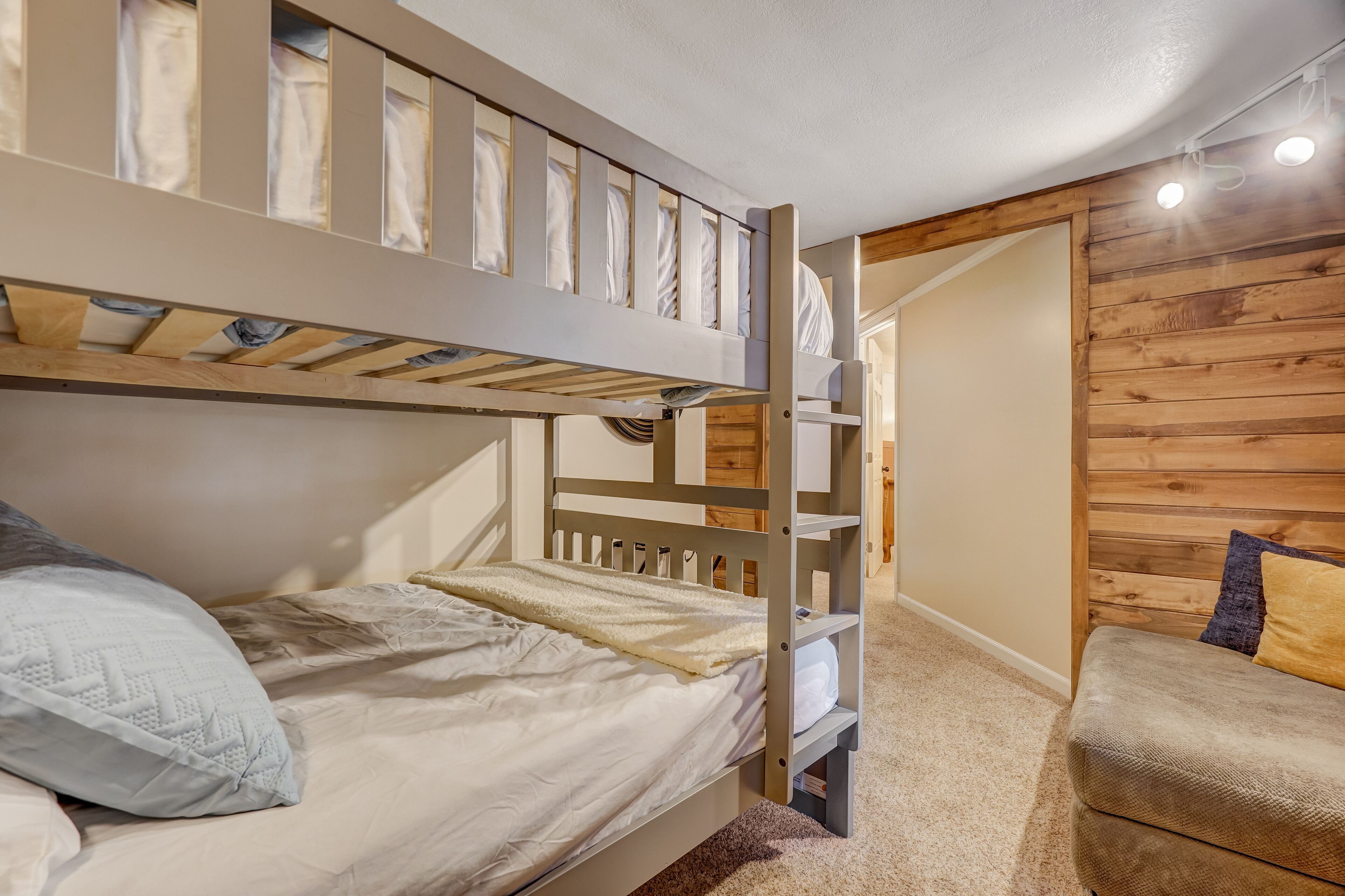 Een stapelbed met een onderbed, een enkel bed en een klein slaapbankje.