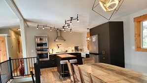 A modern kitchen with a wooden dining table, bar stools, and a built-in oven. - Altitude Adjustment awaits! Large and spacious, perfect for a family getaway  (Star Valley Ranch)