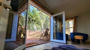 An open sliding glass door leading to an outdoor deck with a wooden chair and a blue chair inside. - Altitude Adjustment awaits! Large and spacious, perfect for a family getaway  (Star Valley Ranch)