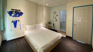Una habitación de hotel con una cama grande, una zona de ducha y una pared decorada con una obra de arte azul y blanca.