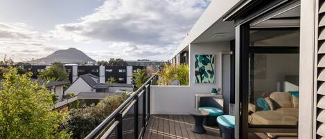 Enjoy breathtaking views of the surrounding mountains from this balcony, featuring a sofa and table.