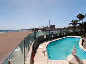 Enjoy a serene beachfront setting with a clear ocean view, a swimming pool with a curved design and a mermaid statue, and access to the sandy beach.
