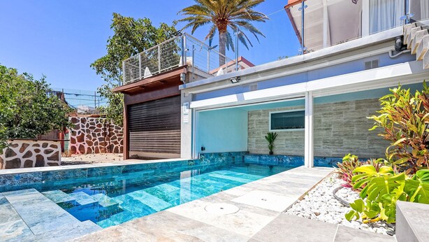 A modern house with a swimming pool, stone walls, and a palm tree. - Villa Parralito Ingenio by Interhome (Maspalomas)