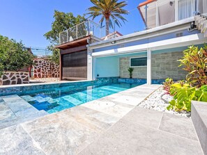 A modern house with a swimming pool, stone walls, and a palm tree. - Villa Parralito Ingenio by Interhome (Maspalomas)