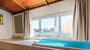 A room with a tiled floor, a window with curtains, and a pool. - Villa Parralito Ingenio by Interhome (Maspalomas)