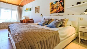 A spacious bedroom with a large bed, a wooden ceiling, a painting on the wall, and a window with curtains. - Villa Parralito Ingenio by Interhome (Maspalomas)