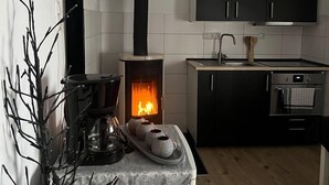 Uma cozinha moderna com lareira a lenha, armários pretos e uma pequena área de jantar com uma bandeja de xícaras.