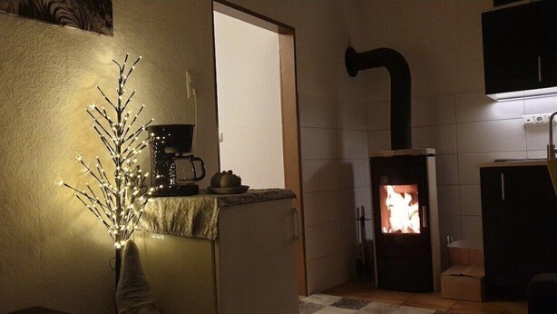 Uma cozinha acolhedora com lareira a lenha, cafeteira e uma árvore decorativa.