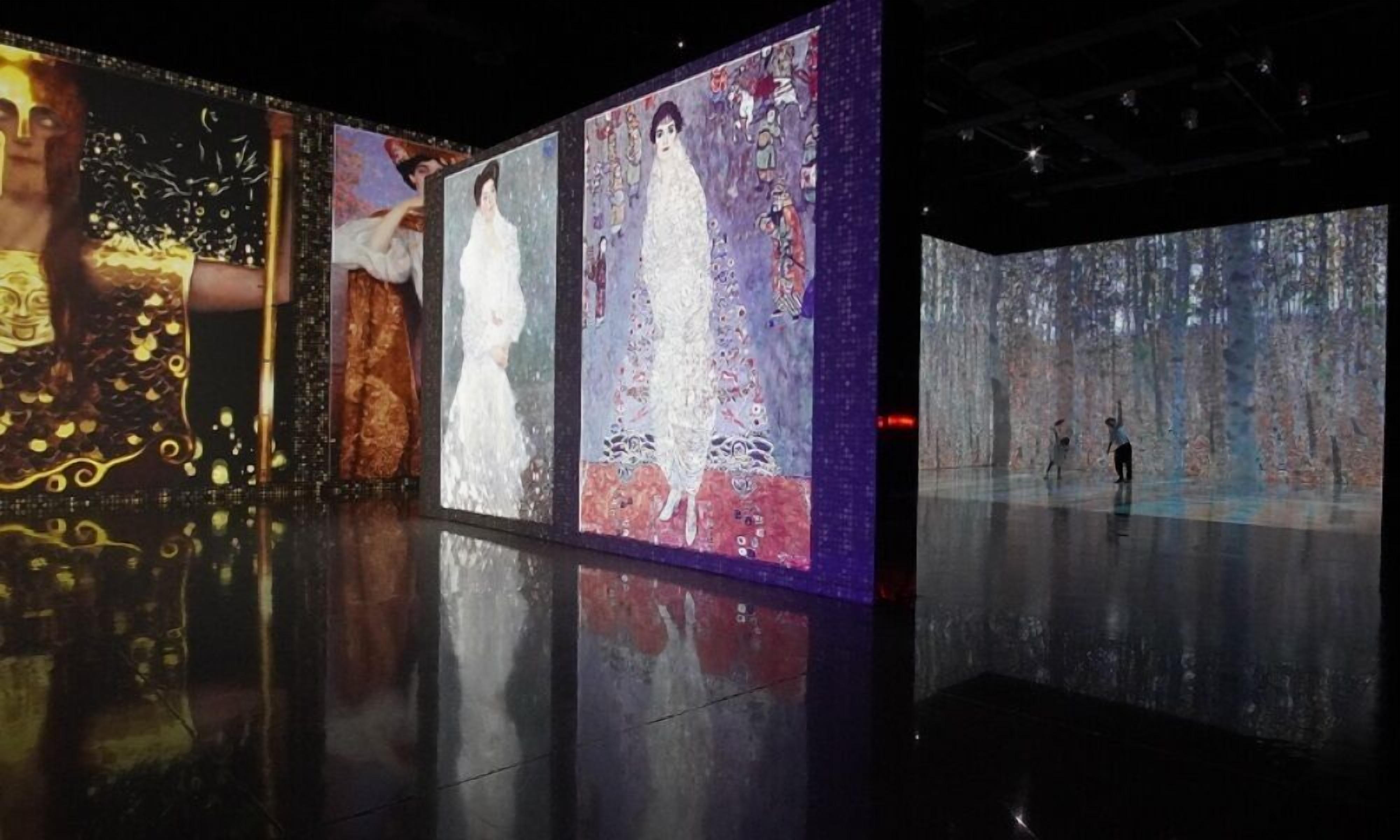 A modern art gallery with large, colorful paintings and a reflective floor.