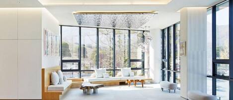 A modern living room with a large window, a sofa, a coffee table, and a dog.