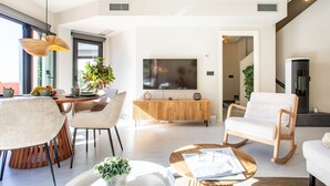 Un salon moderne doté d’un grand téléviseur, de sièges confortables, d’un coin repas et d’un escalier.