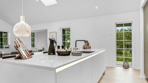 Une cuisine moderne dotée d’un îlot central, d’un luminaire suspendu et offrant une vue sur l’extérieur.