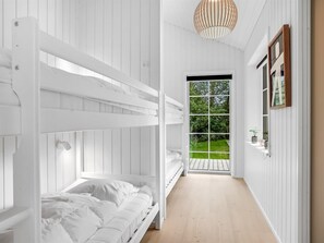 Une chambre avec des lits superposés donnant sur un jardin, grâce à une grande fenêtre.
