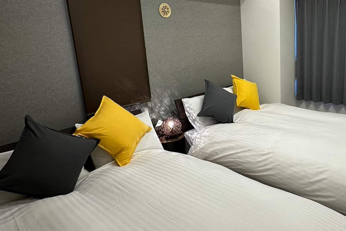 A hotel room with two beds, a heater, and a window with curtains.