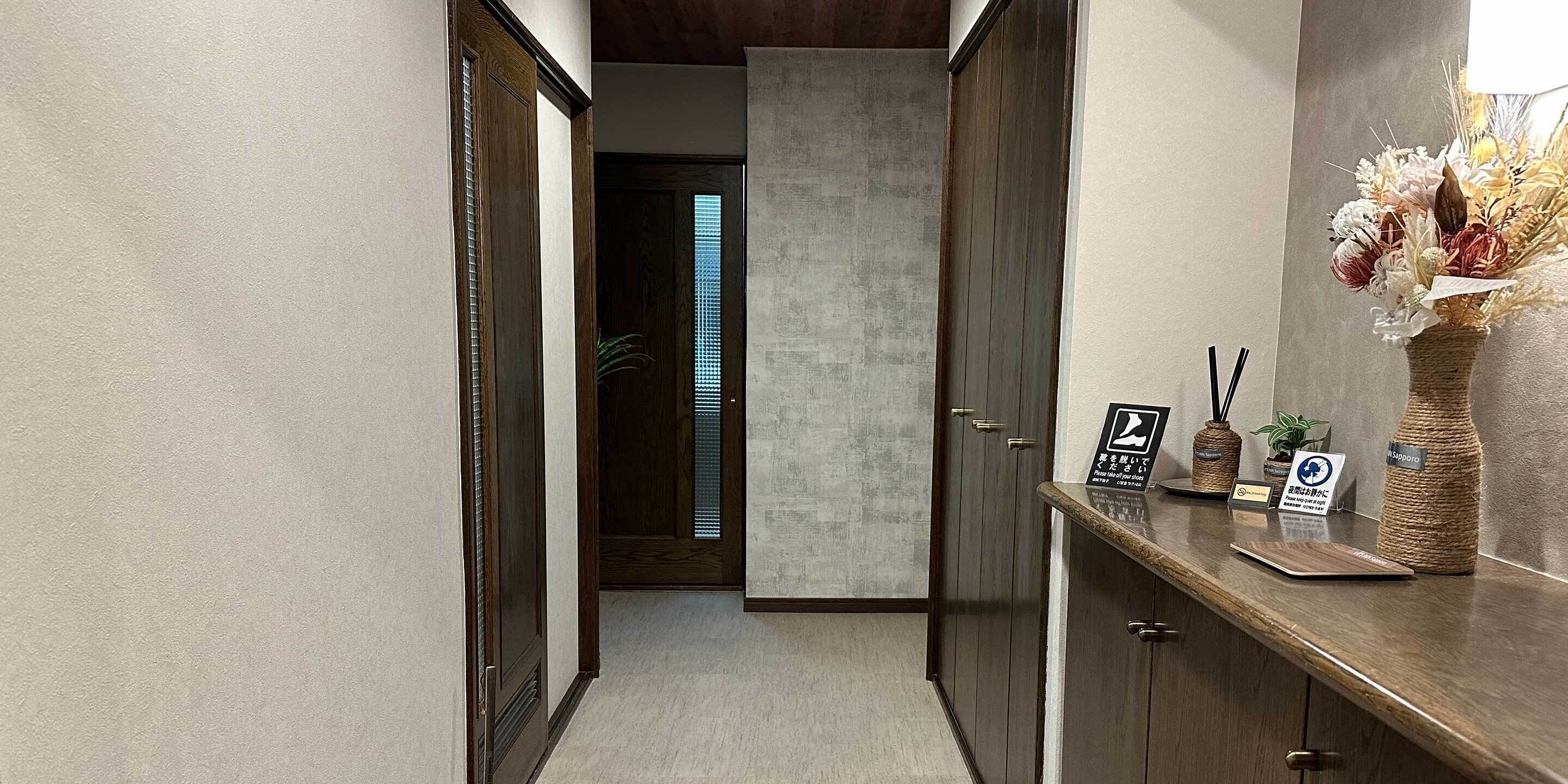 A hallway with wooden doors, a reception desk with a vase of flowers, and a sign indicating a pet-friendly policy.