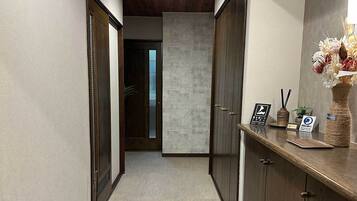 A hallway with wooden doors, a reception desk with a vase of flowers, and a sign indicating a pet-friendly policy.