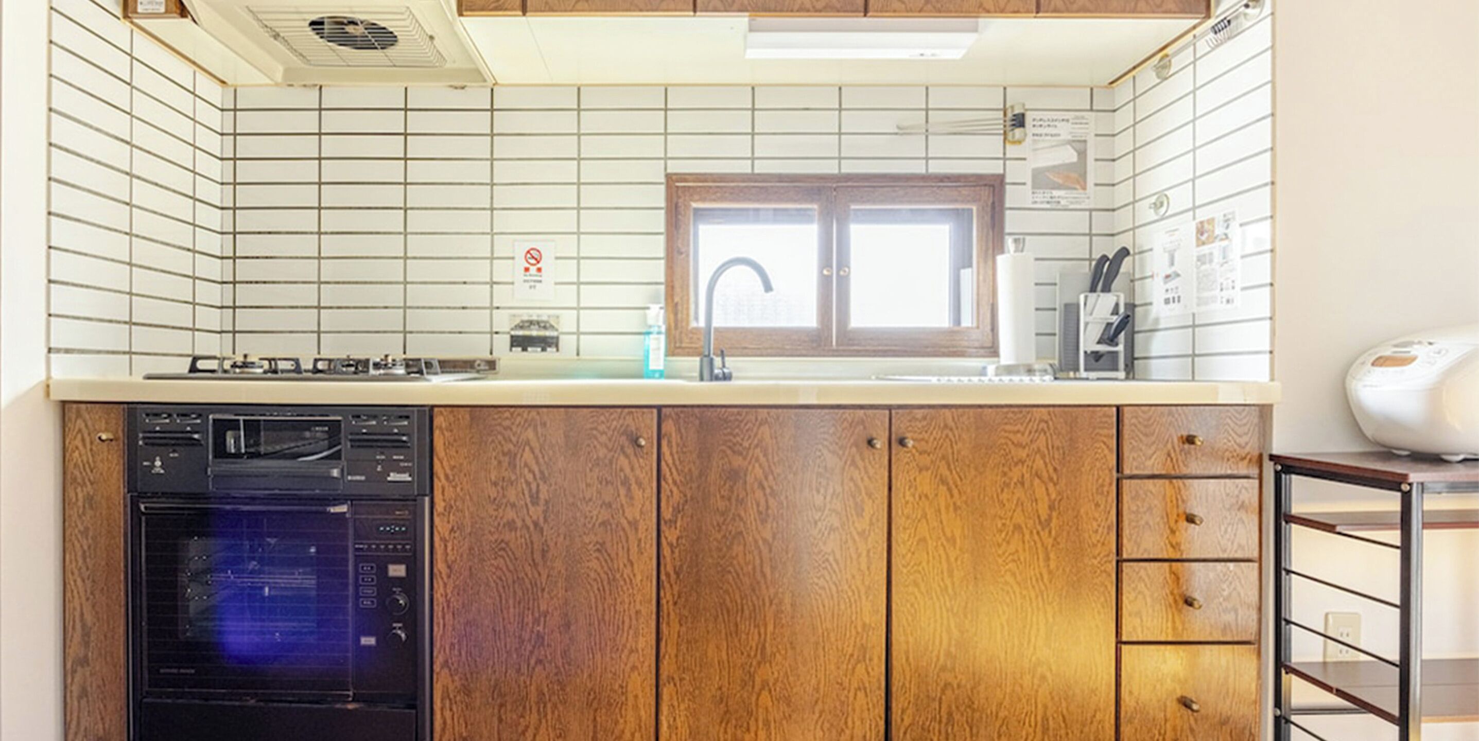 A kitchen with wooden cabinets, a built-in dishwasher, a stove, and a window above the sink.