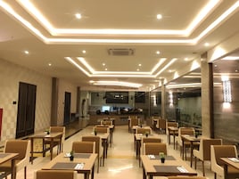 Un comedor amplio con varias mesas y sillas, una barra central y un diseño moderno en el techo.