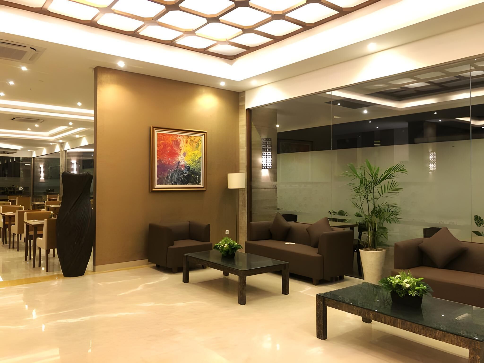 A modern lobby with seating, a large abstract painting, and a glass partition.