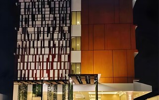 A modern building facade with a geometric pattern and a warm-toned wooden section.