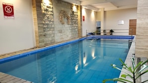 An indoor swimming pool with a stone wall and a blue tiled floor. - Lynn Hotel Mojokerto (Mojokerto)