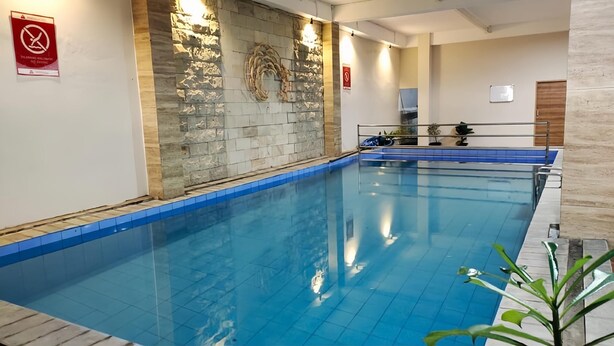 En inomhuspool med en vägg av sten och ett blått kakelgolv.
