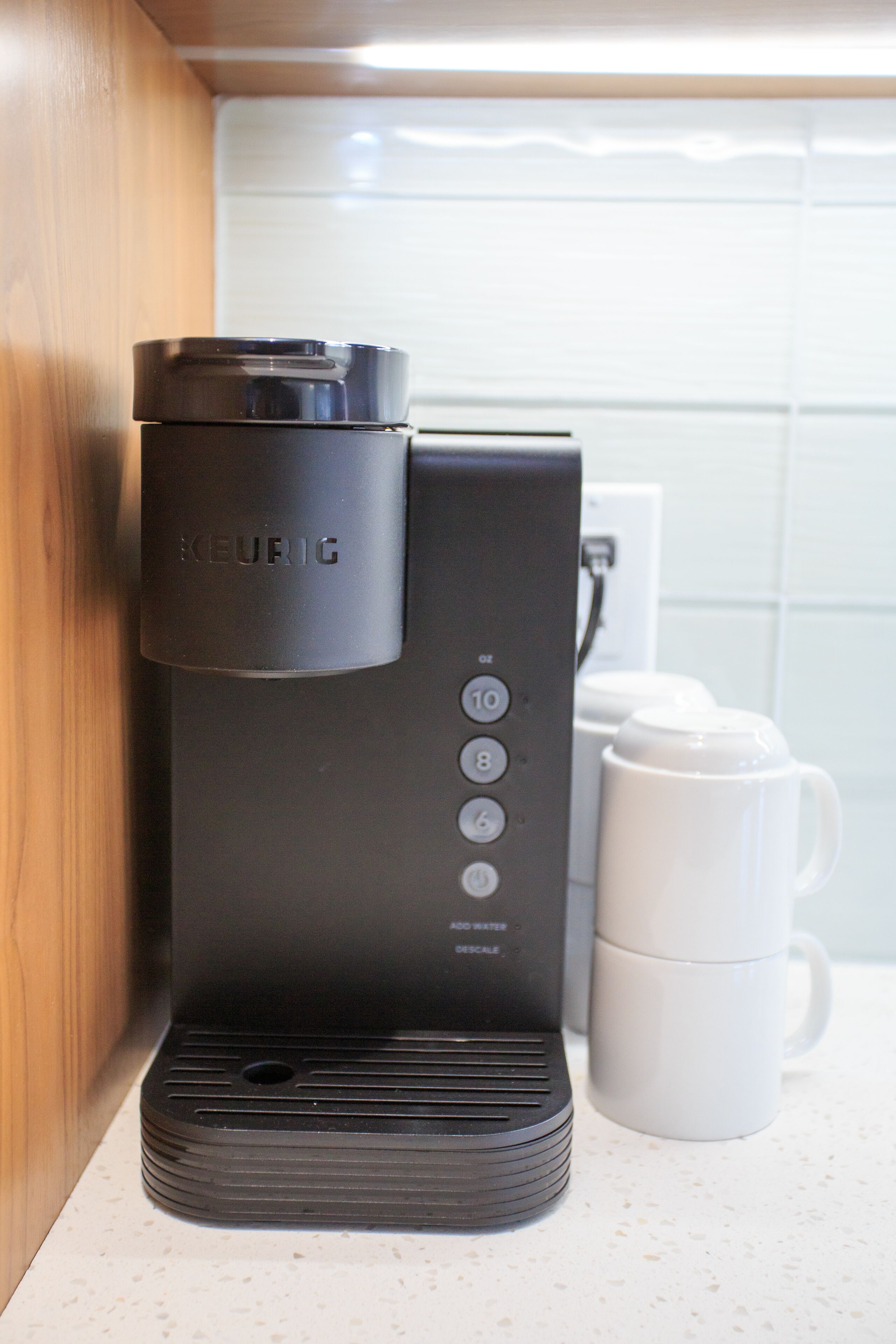 A Keurig coffee maker on a kitchen counter next to a white mug.