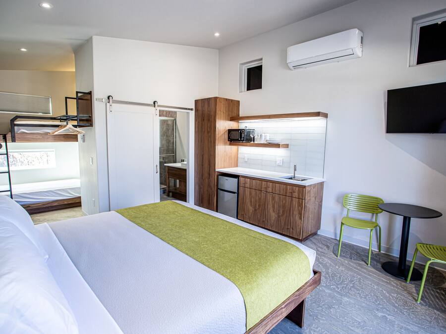 A hotel room with a bed, kitchenette, and seating area.