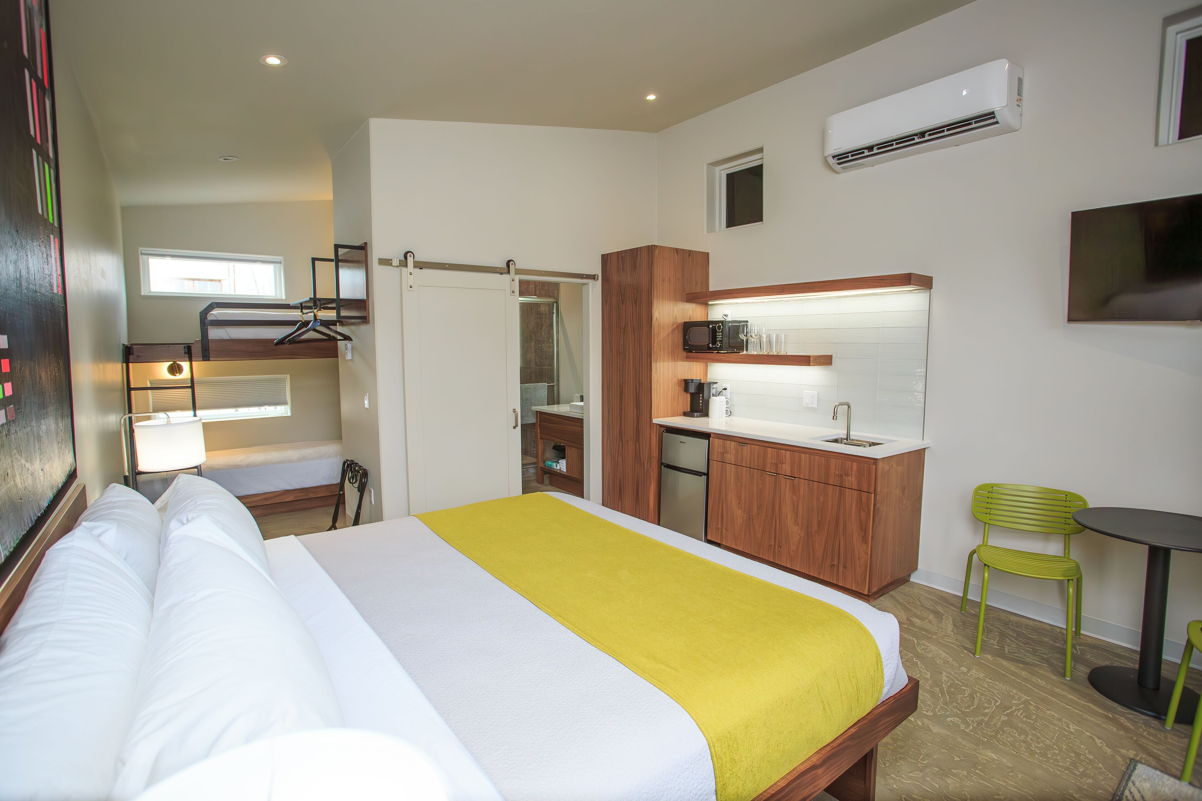 Ein Hotelzimmer mit Bett, einer Küchenzeile, einem Badezimmer und einem Essbereich.