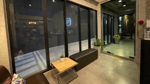 A modern interior with large windows, a seating area with a table and chairs, and a reception desk. - Loft Space Hotel (Ranong)
