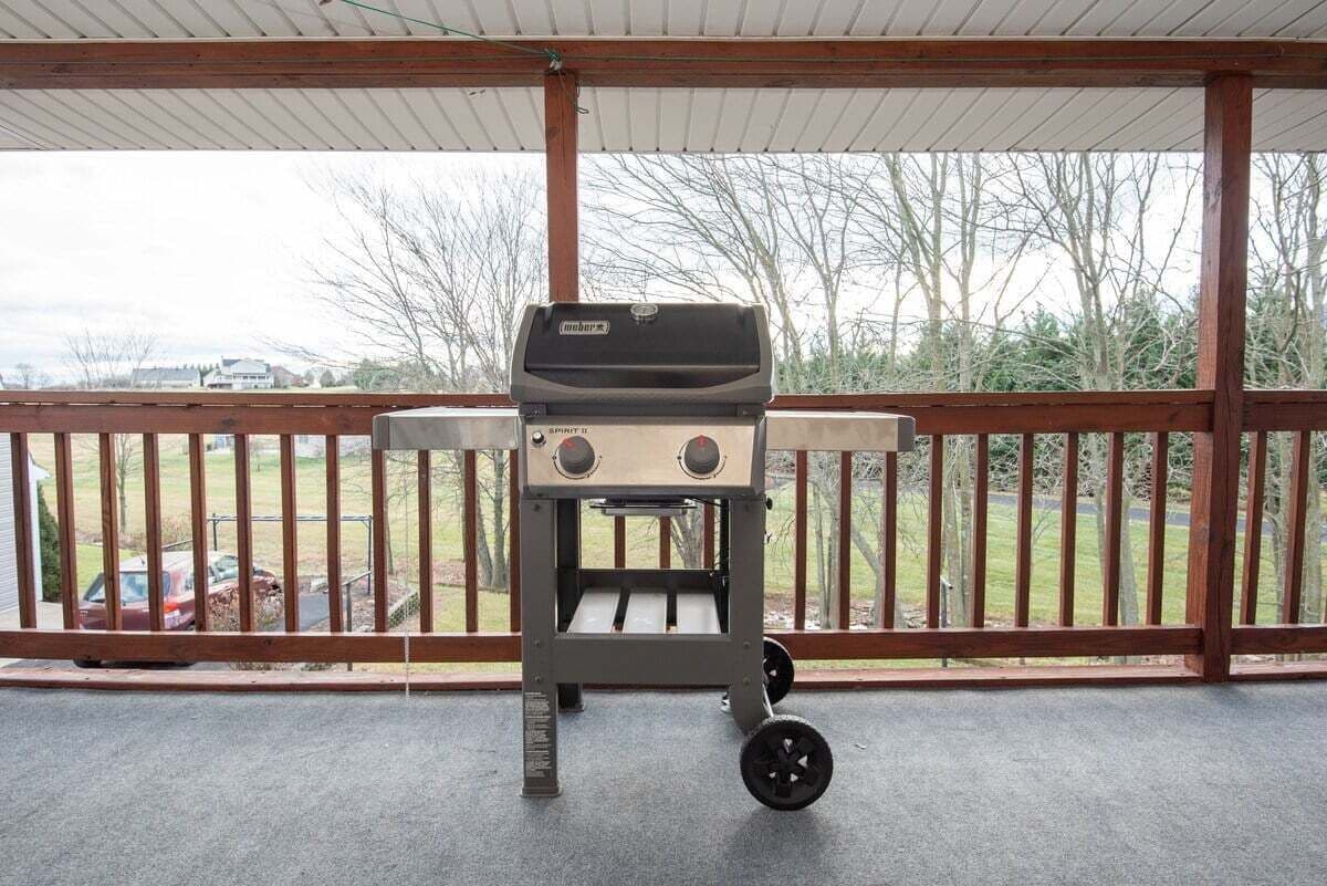 A portable grill on a covered patio with a view of a residential area.