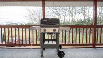 A portable grill on a covered patio with a view of a residential area.
