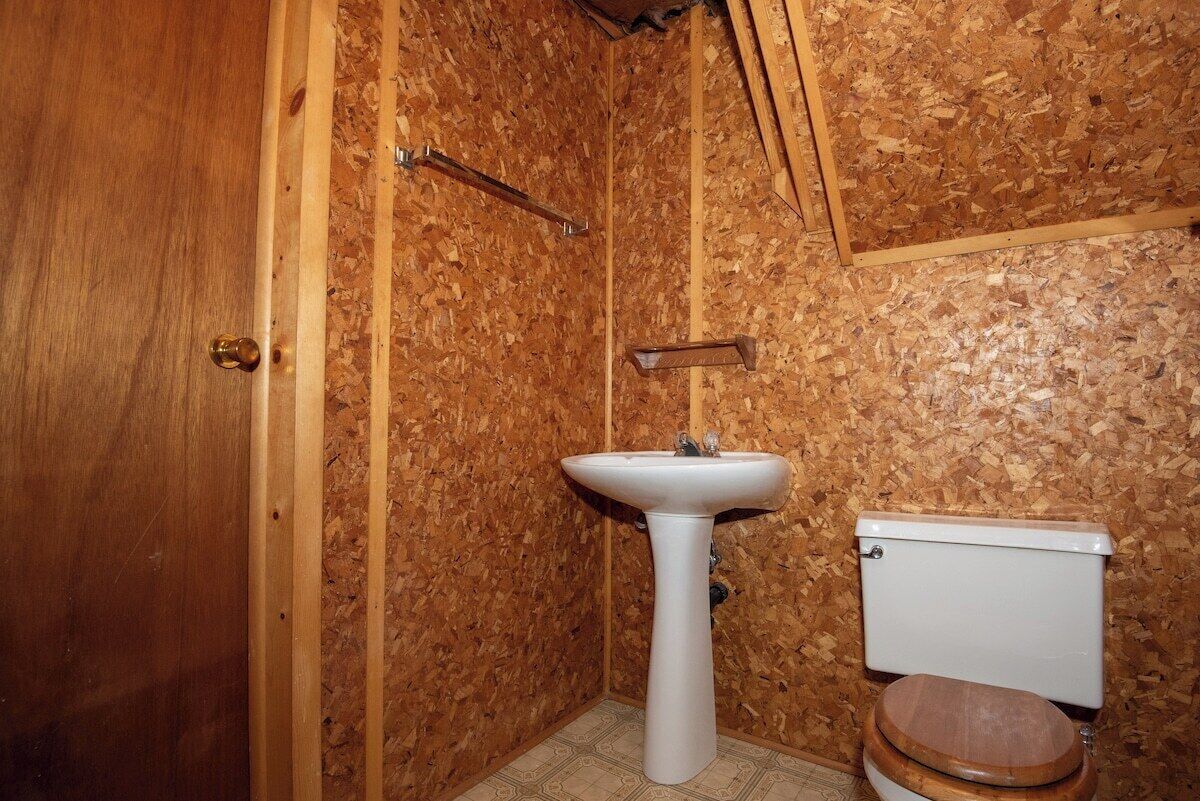Un bagno con una porta in legno, un lavandino bianco e un water.
