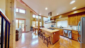 A spacious kitchen with wooden cabinets, a large island, and a view to the outside.