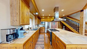 A modern kitchen with wooden cabinets, stainless steel appliances, and a central island. - Coyote Run - 4 (Moab)