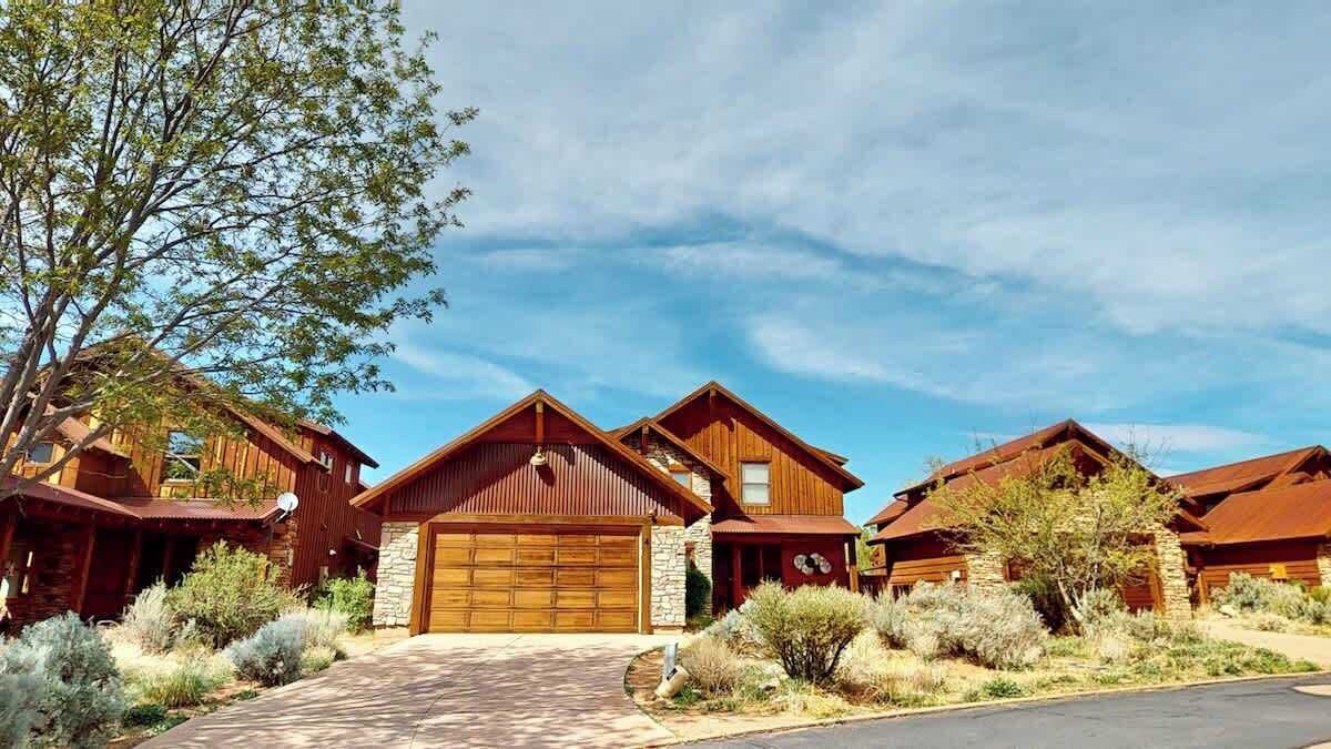 A multi-story wooden house with a stone foundation, a garage, and a driveway.