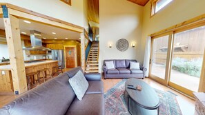A spacious living area with a sofa, a coffee table, and a staircase leading to an upper level. - Coyote Run - 4 (Moab)