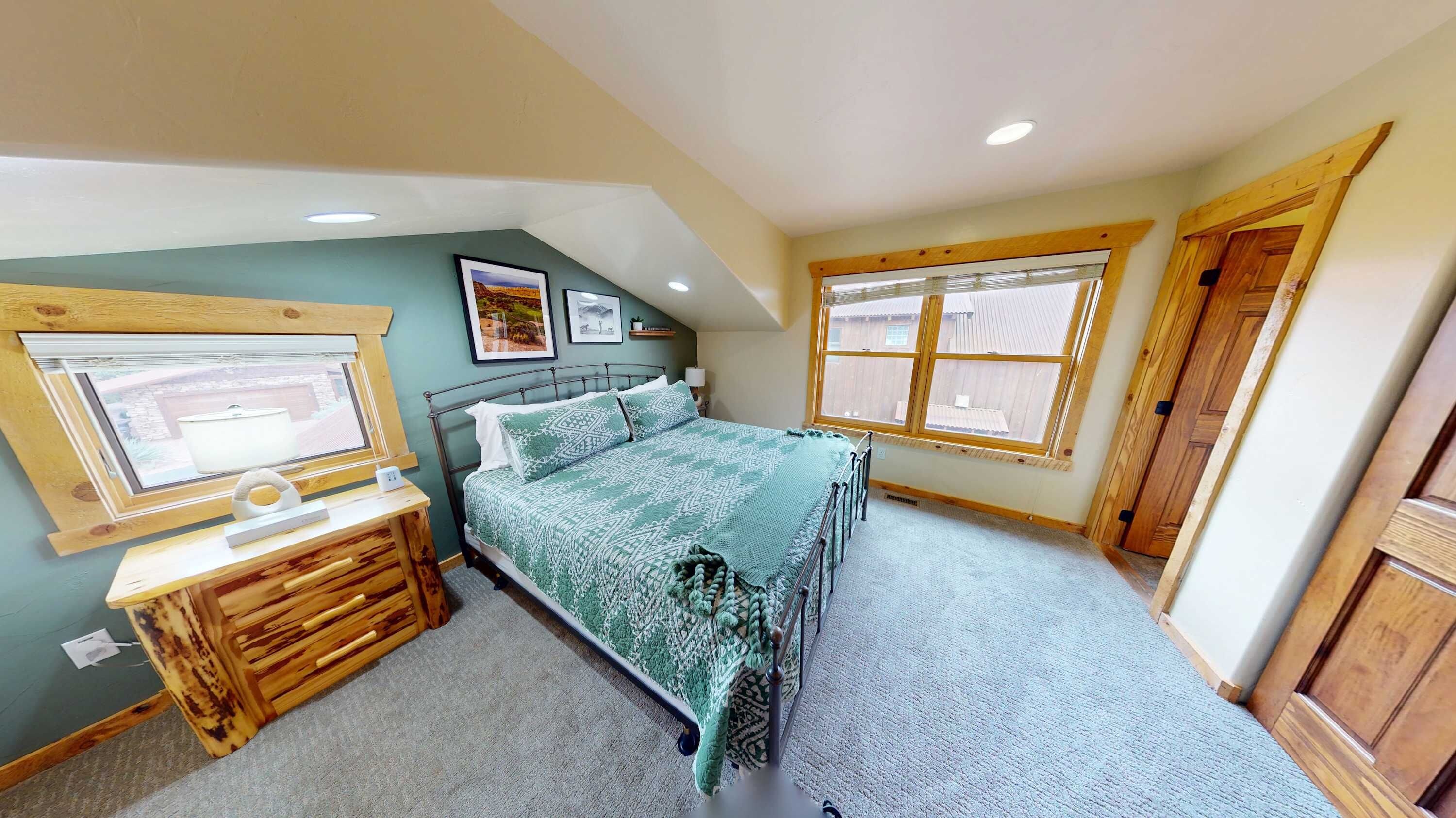 A bedroom with a bed, a desk, and a window.