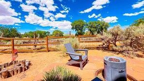 An outdoor patio with a wooden fence, a chair, and a barbecue grill. - Coyote Run - 4 (Moab)