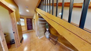 A wooden staircase with a handrail, a potted plant, and a bench at the bottom.