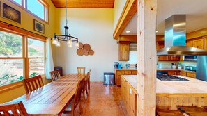 A spacious kitchen with wooden cabinets, a stainless steel range hood, and a dining area with a wooden table and chairs. - Coyote Run - 4 (Moab)