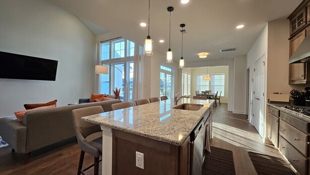 A spacious kitchen with a large island, modern pendant lighting, and a dining area with a view of the outdoors.
