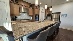 A modern kitchen with granite countertops, stainless steel appliances, and wooden cabinets.