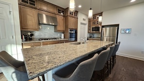 Una cocina moderna con encimeras de granito, electrodomésticos de acero inoxidable y armarios de madera.