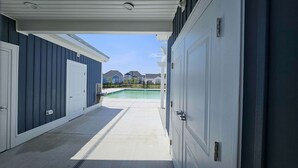 A covered garage entrance leading to a swimming pool area with a view of neighboring houses.