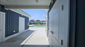 Entrada de garaje techada que da a una zona de piscina con vistas a casas vecinas.