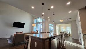A modern kitchen with a central island, pendant lighting, and a large window providing natural light.
